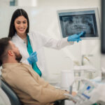 Dentist showing teeth x-ray to patient in modern clinic