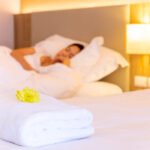 towel-with-flower-on-bed-in-hotel-room-with-woman-2025-10-16-08-48-23-utc