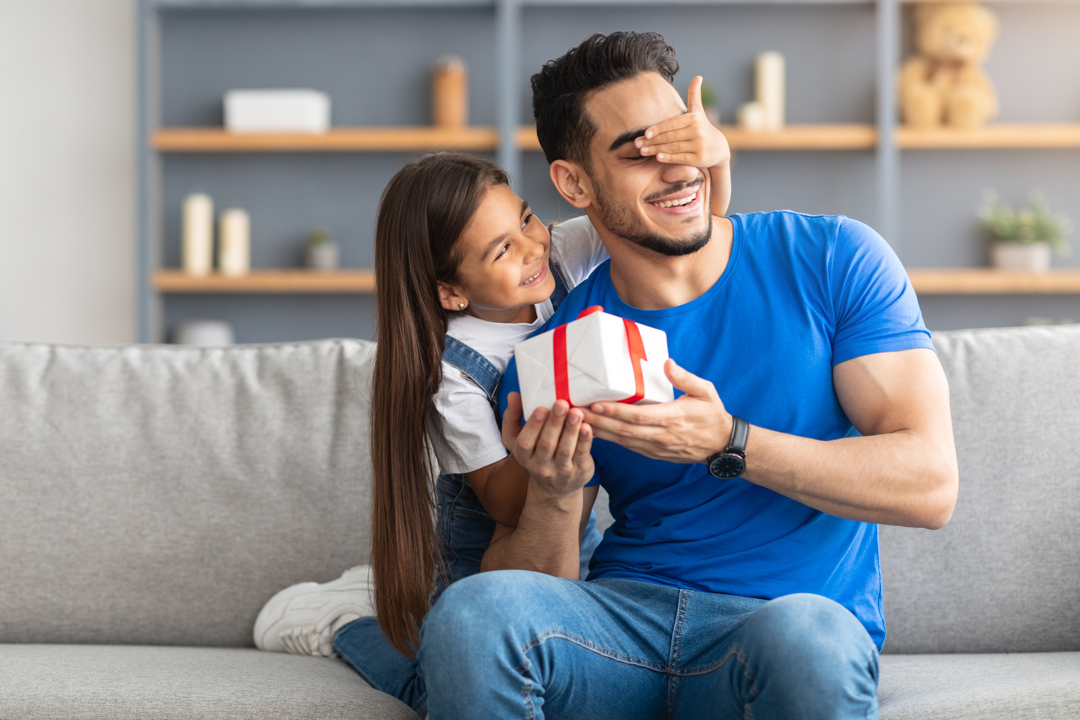 Cautela no consumo e busca por utilidade impulsionam compras de vestuário no Dia dos Pais em MT Loving girl celebrating father's day, greeting excited dad with box